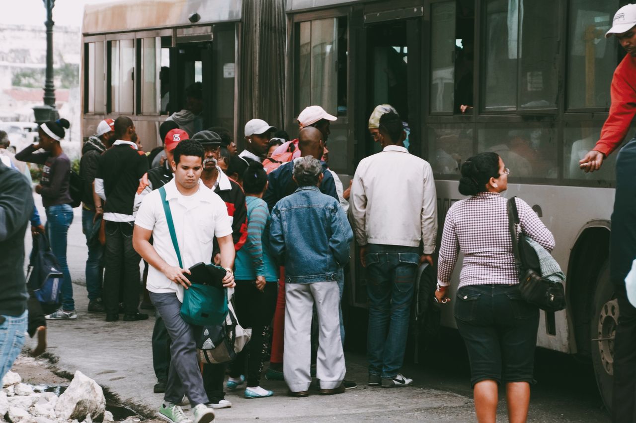 A bustling city scene of diverse people boarding a public transport bus.