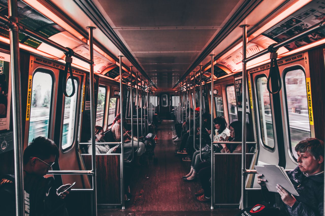 Passengers travel inside a well-lit subway train during the day, showcasing modern urban life.