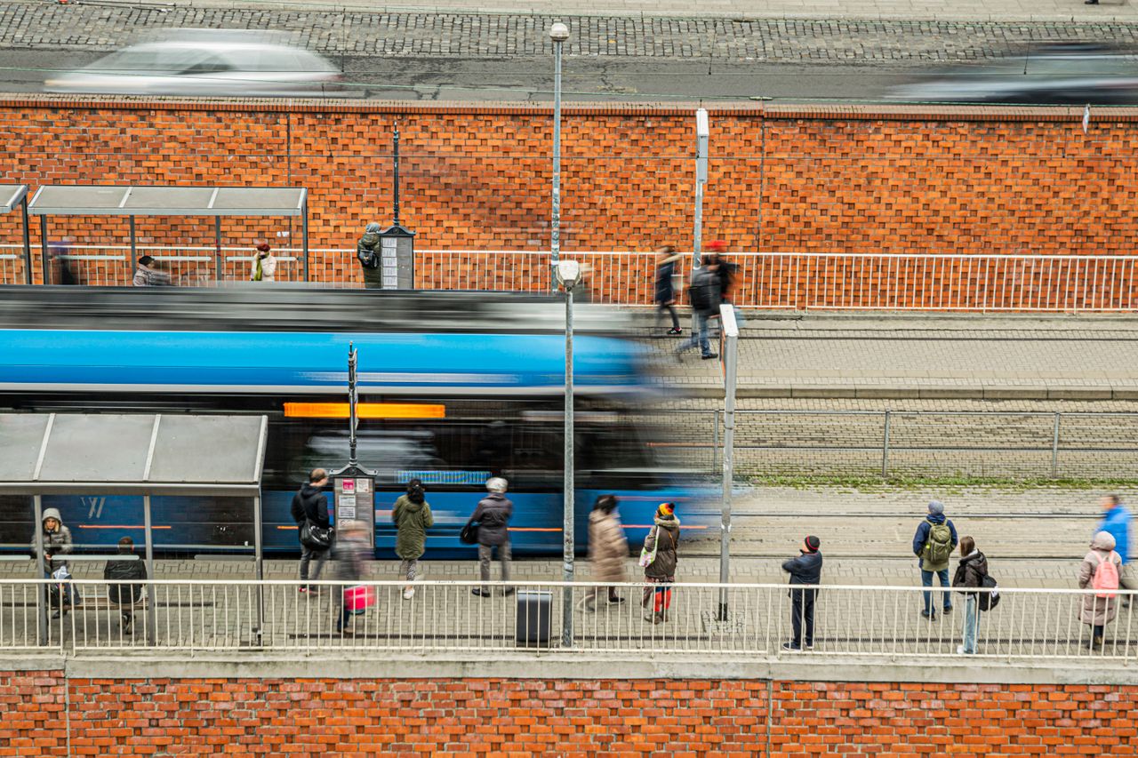 People waiting at a tram station, capturing urban daily life with motion blur.