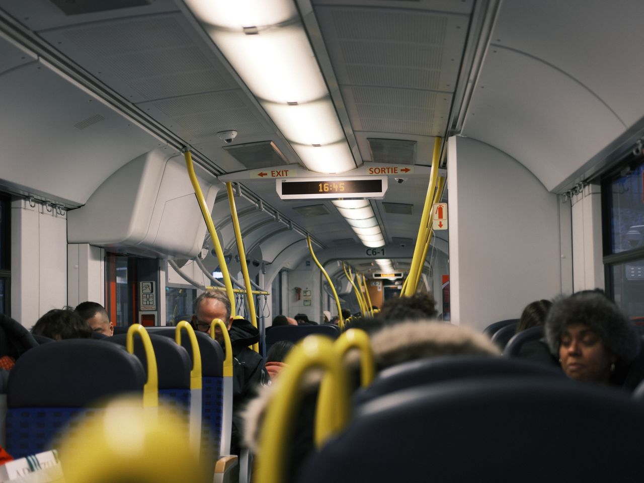 Passengers commuting inside a modern public train during the day.